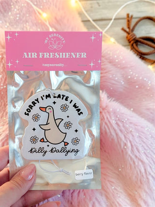 A hand holds a packaged air freshener sticker featuring a cartoon duck with the text 'Sorry I'm Late I Was Dilly Ballyping' and 'Berry flavor.' The product is in a clear pouch with a pink header card reading 'Air Freshener' and the brand 'My Sweetly.