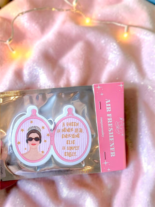 A pink and white enamel pin set in its packaging, featuring a mirror-themed design with one mirror showing a woman in sunglasses and the other reading 'A QUEEN IS NEVER LOVE. EVERYONE ELSE IS SIMPLY ENGLY.