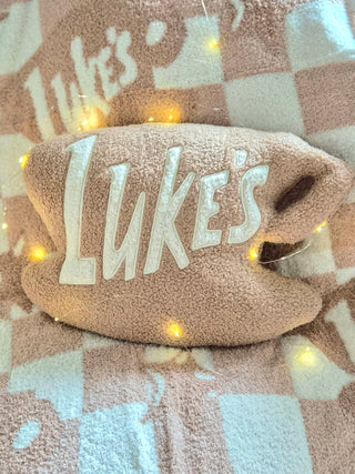 Plush pillow with 'Luke's' embroidery on a checkered blanket